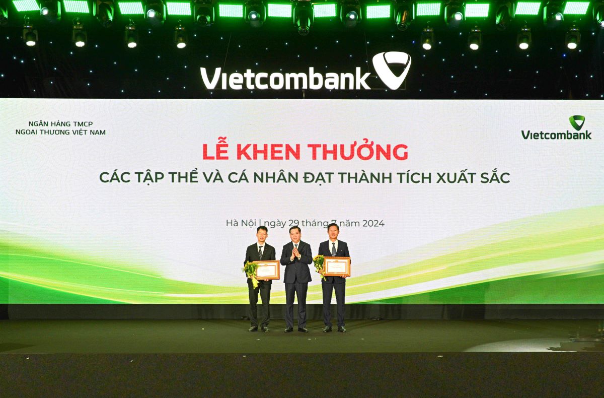 Đồng chí Nguyễn Long Hải - Ủy viên dự khuyết BCH Trung ương Đảng, Bí thư Đảng ủy Khối DNTW (đứng giữa) trao Bằng khen và tặng hoa cho 2 đảng bộ vinh dự nhận Bằng khen của Đảng ủy Khối DNTW. Ảnh: Vietcombank.