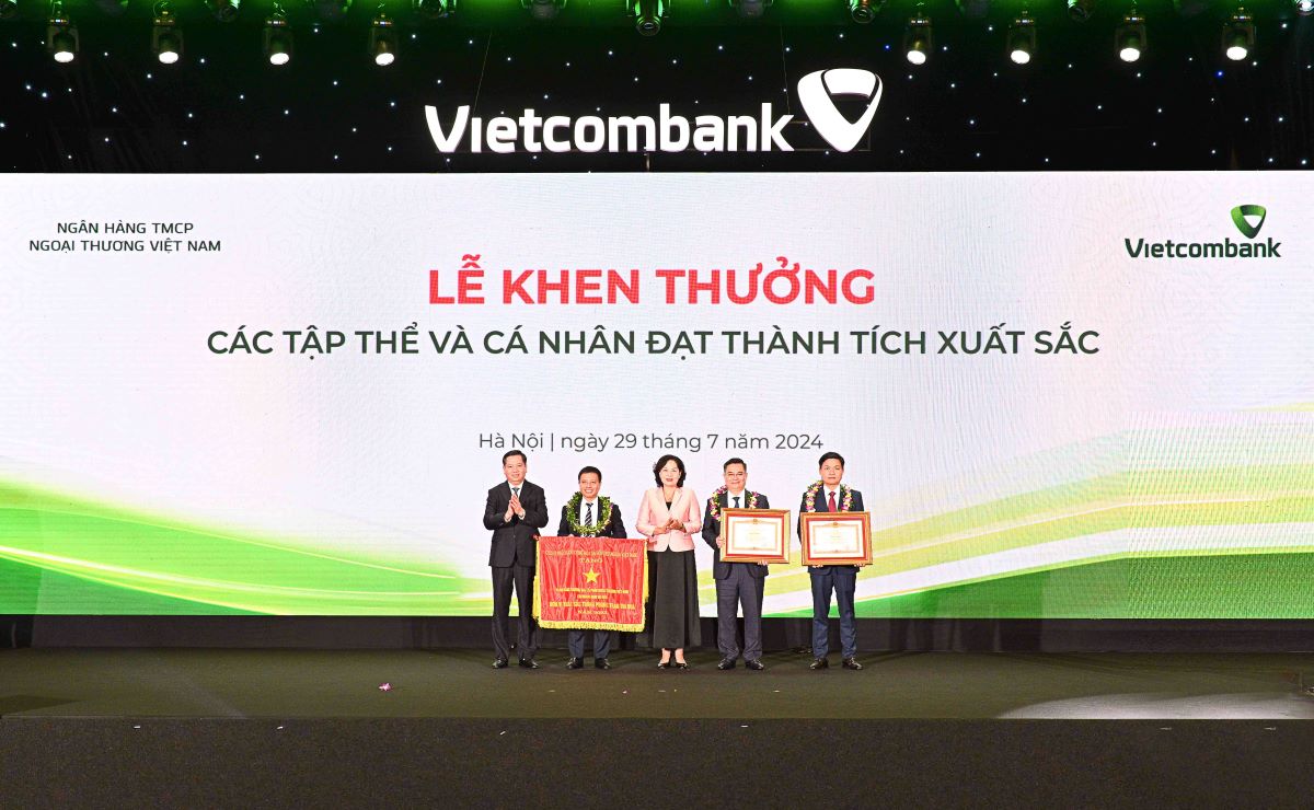 Đồng chí Nguyễn Thị Hồng - Ủy viên BCH Trung ương Đảng, Thống đốc NHNN Việt Nam (đứng giữa) cùng đồng chí Nguyễn Long Hải - Ủy viên dự khuyết BCH Trung ương Đảng, Bí thư Đảng ủy Khối DNTW (ngoài cùng bên trái) trao Cờ, Bằng khen và tặng hoa chúc mừng các tập thể và cá nhân vinh dự nhận Cờ Thi đua của Chính phủ và Bằng khen của Thủ tướng Chính phủ. Ảnh: Vietcombank.